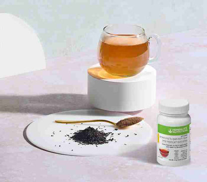 Tea with a spoonful of honey and a bottle of herbal supplement on a white surface.